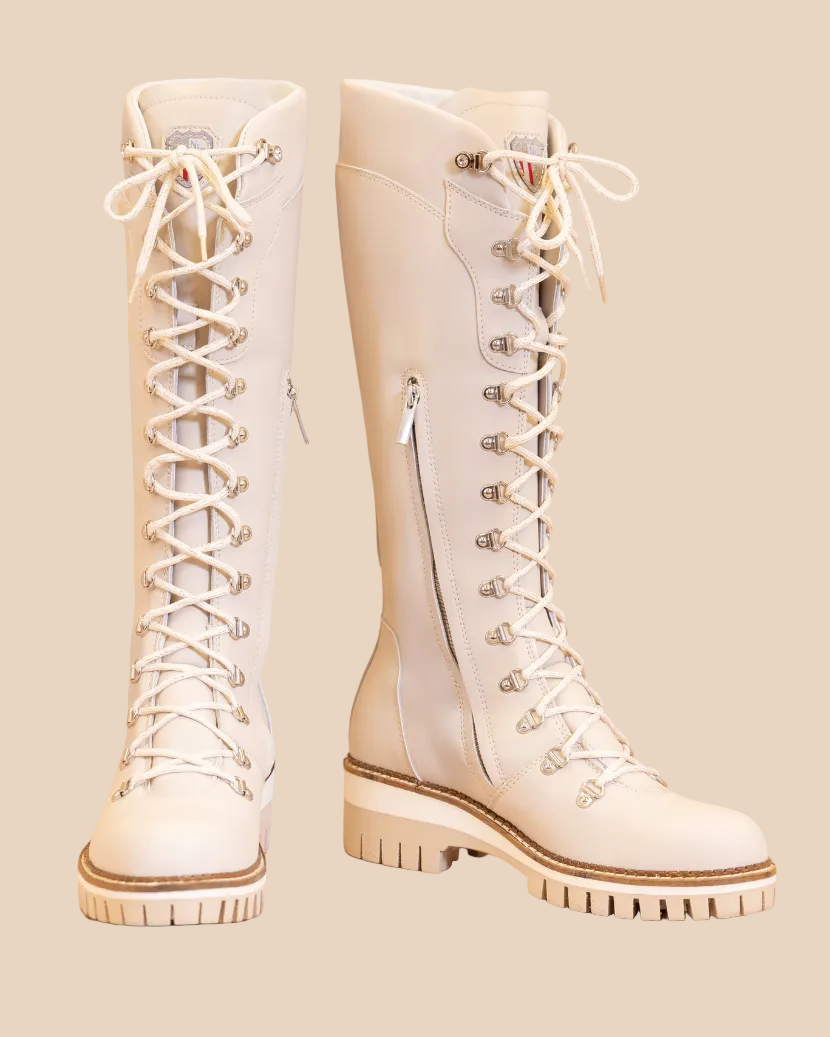 Pair of white knee-high boots with laces on a beige background