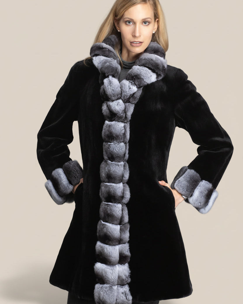 Woman wearing a black coat with gray fur trim on a beige background